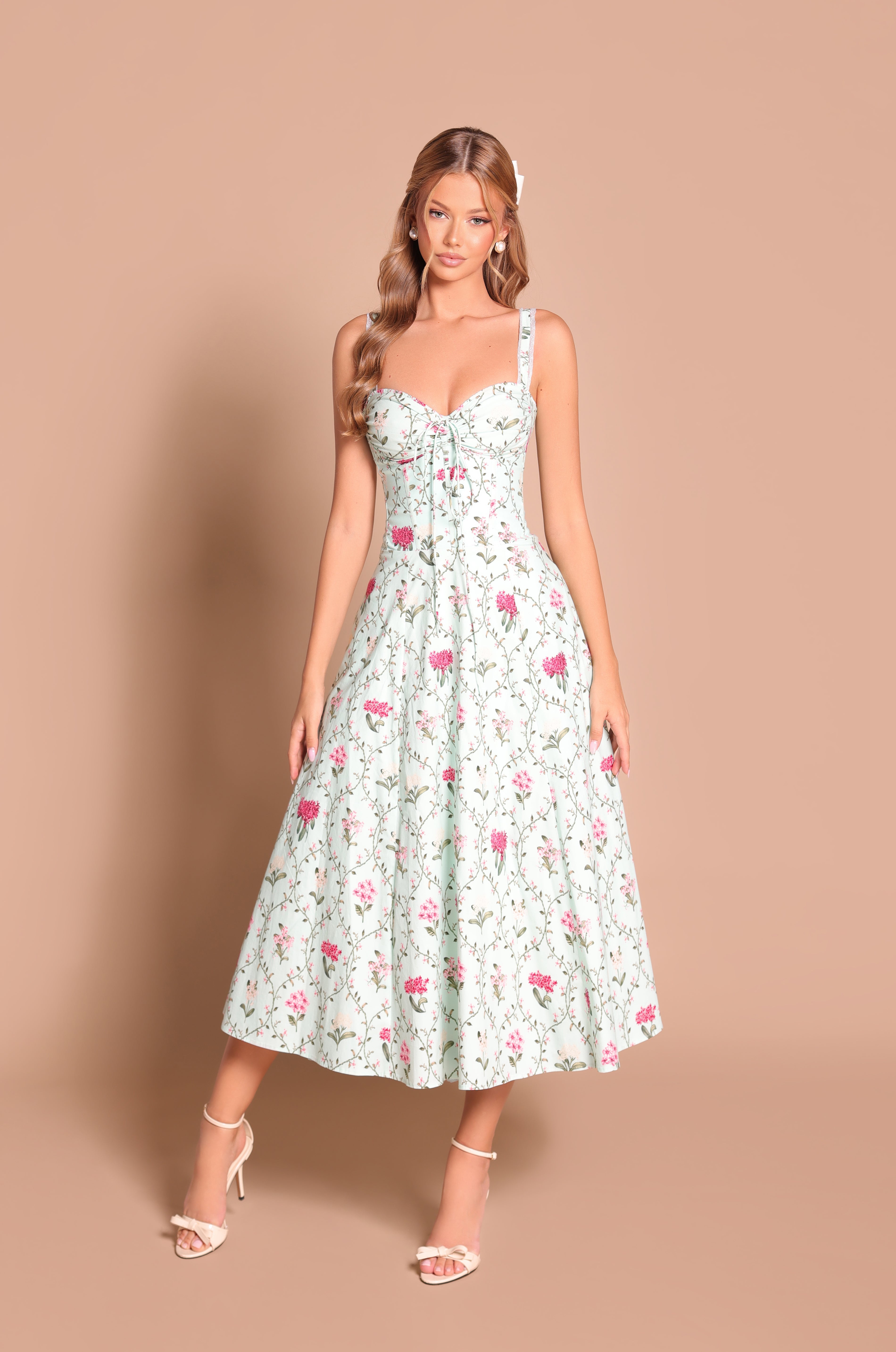 A woman stands against a beige background wearing the Mint Green Floral Casual Midi Dress: Celenia with strappy heels.